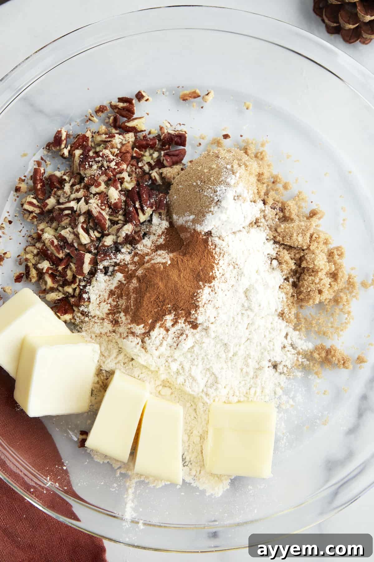 Ingredients for the streusel topping (butter, flour, brown sugar, cinnamon, pecans) gathered in a bowl before mixing.