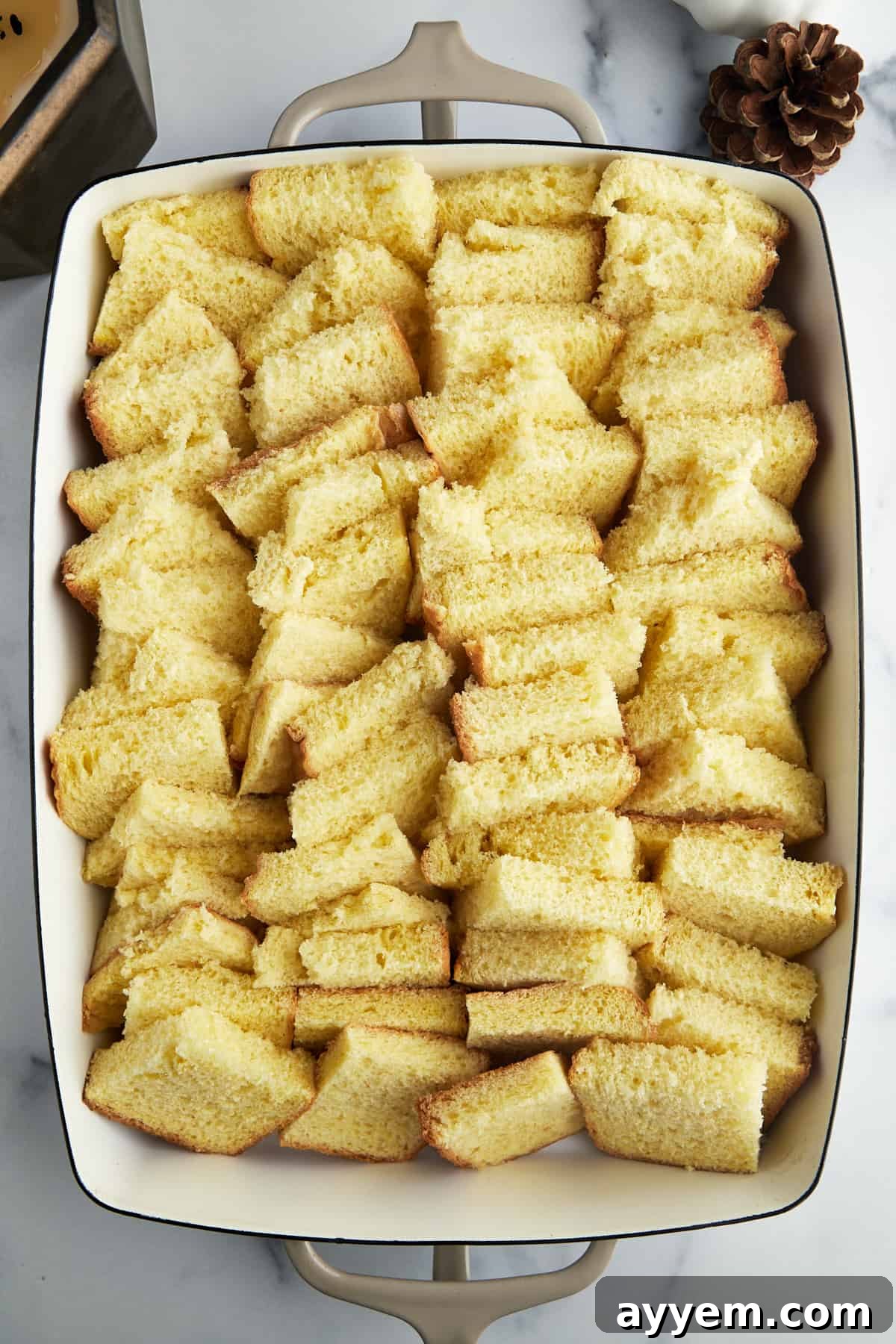 Arranging cubed bread in a single layer in a baking dish, ready for the custard.