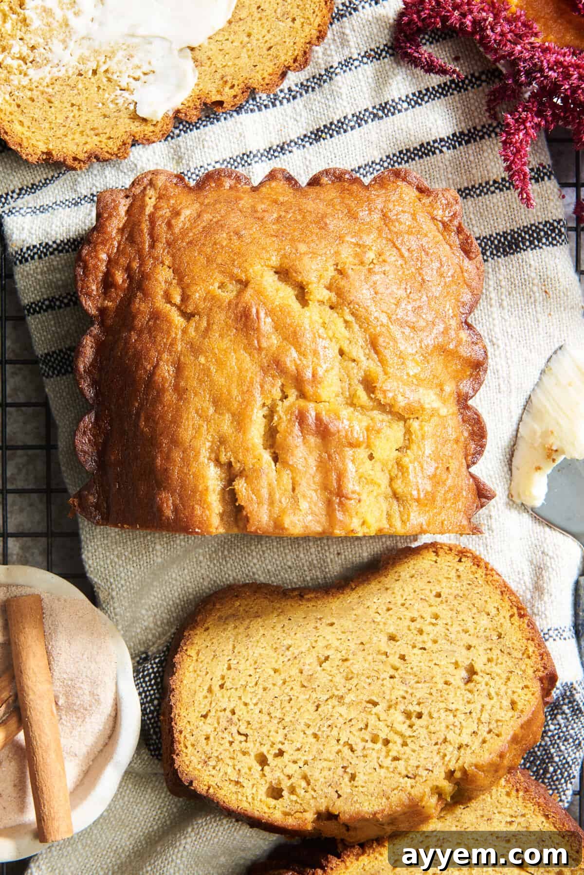 A warm, golden loaf of homemade pumpkin banana bread resting on a cooling rack, with several slices already cut, showcasing its tender, moist interior and delicious texture.
