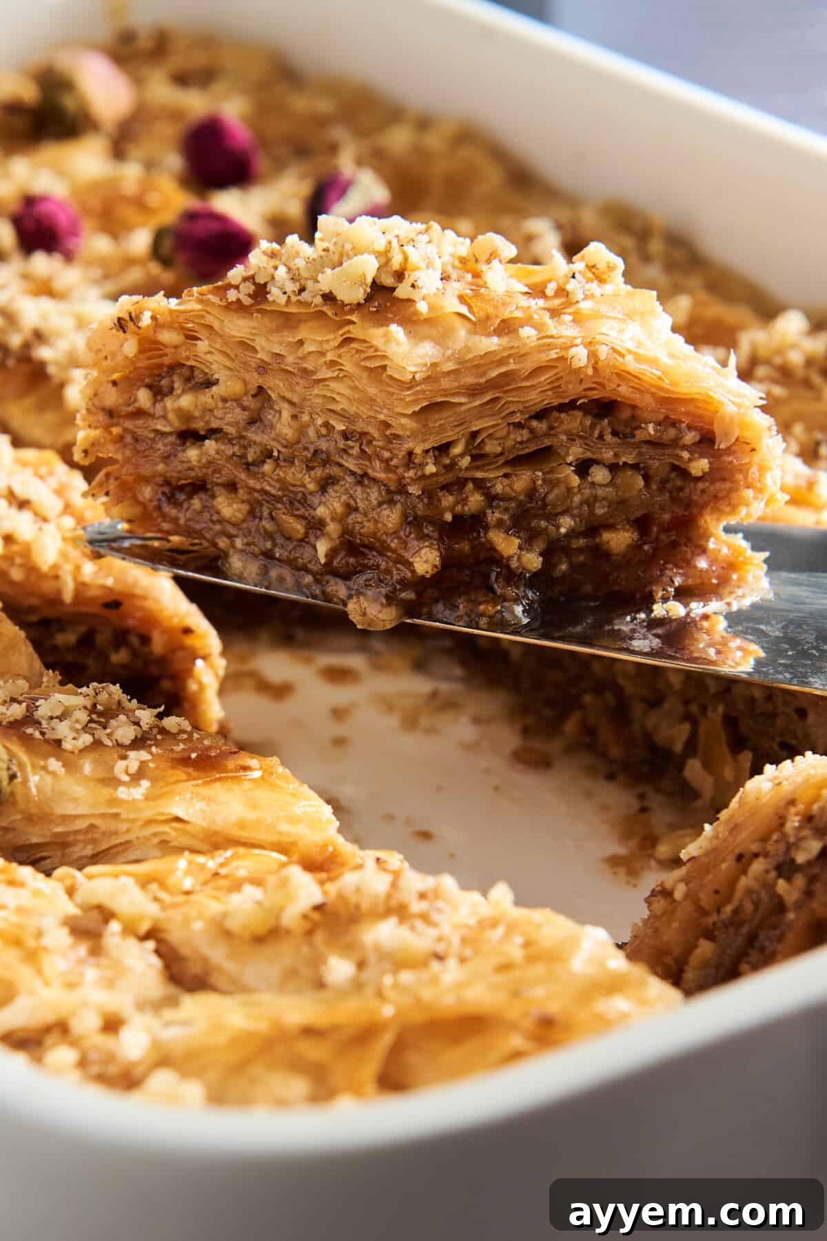 The Ultimate Baklava Recipe Guide 2 A slice of baklava being lifted from a baking dish full of the dessert.