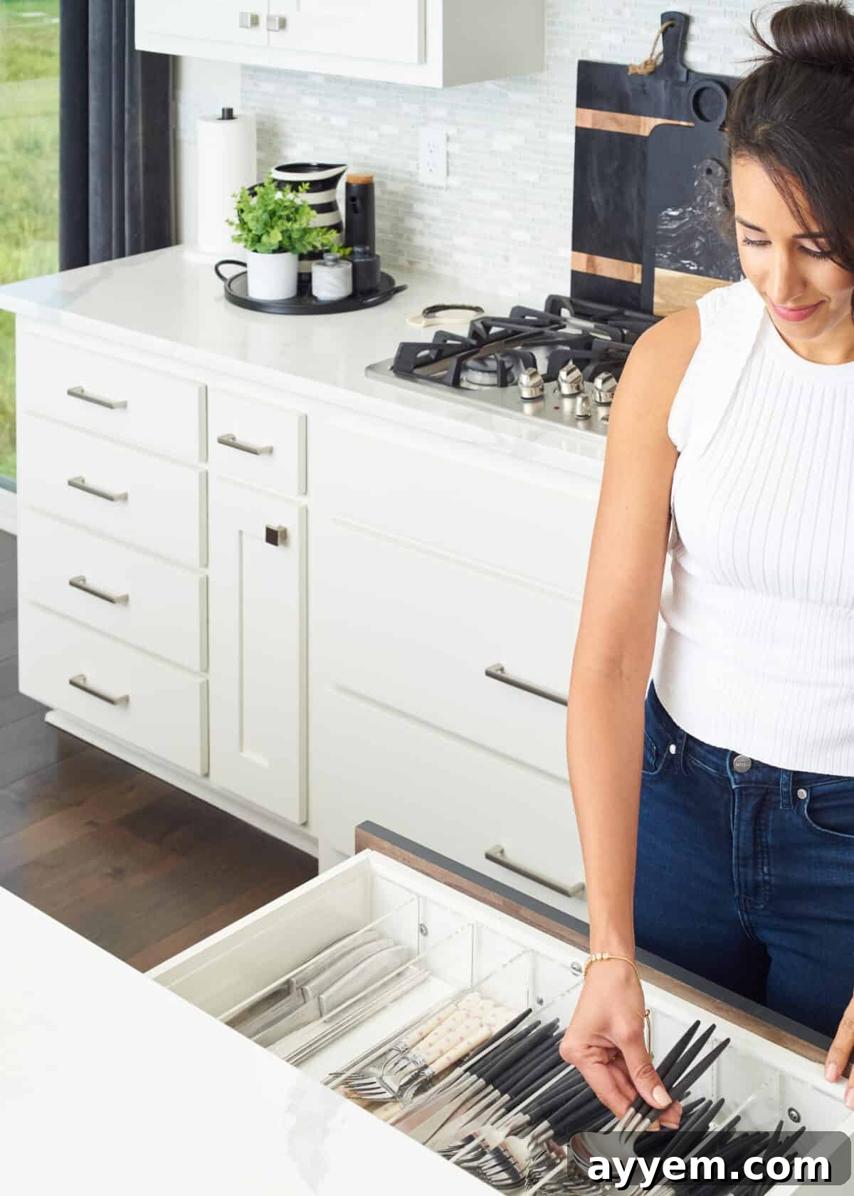 woman placing spoons in kitchen drawer.