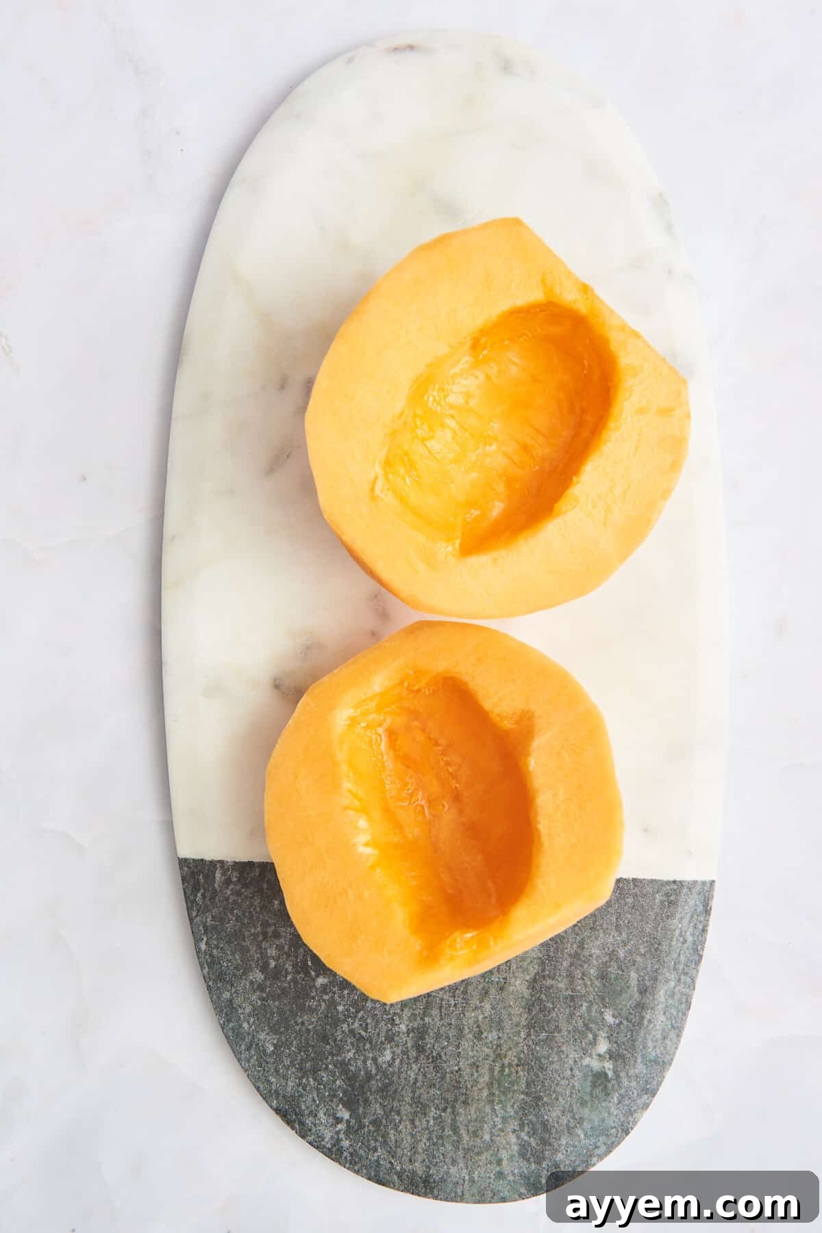 Overhead image of two halves of a perfectly cut cantaloupe fruit, one for slices and one for cubes.