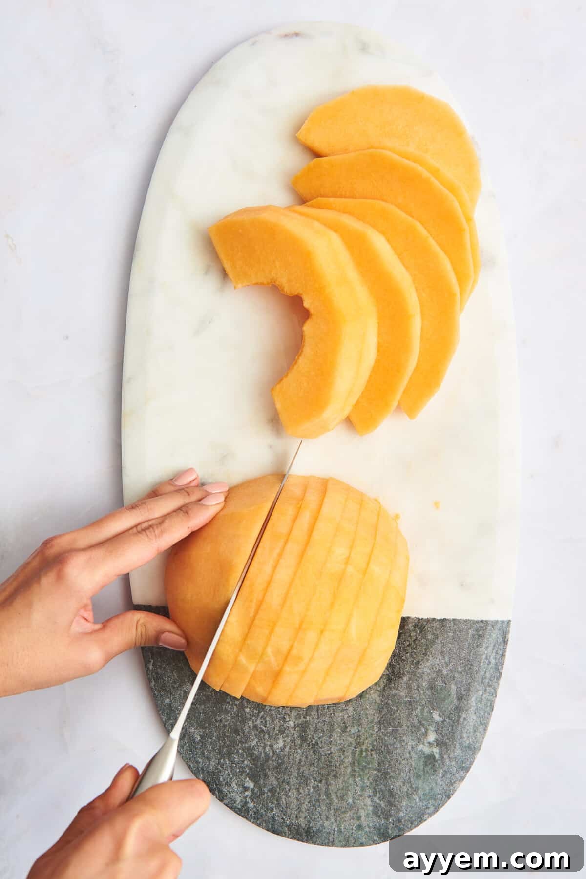 A peeled cantaloupe being sliced into strips, ready for cubing or further processing.