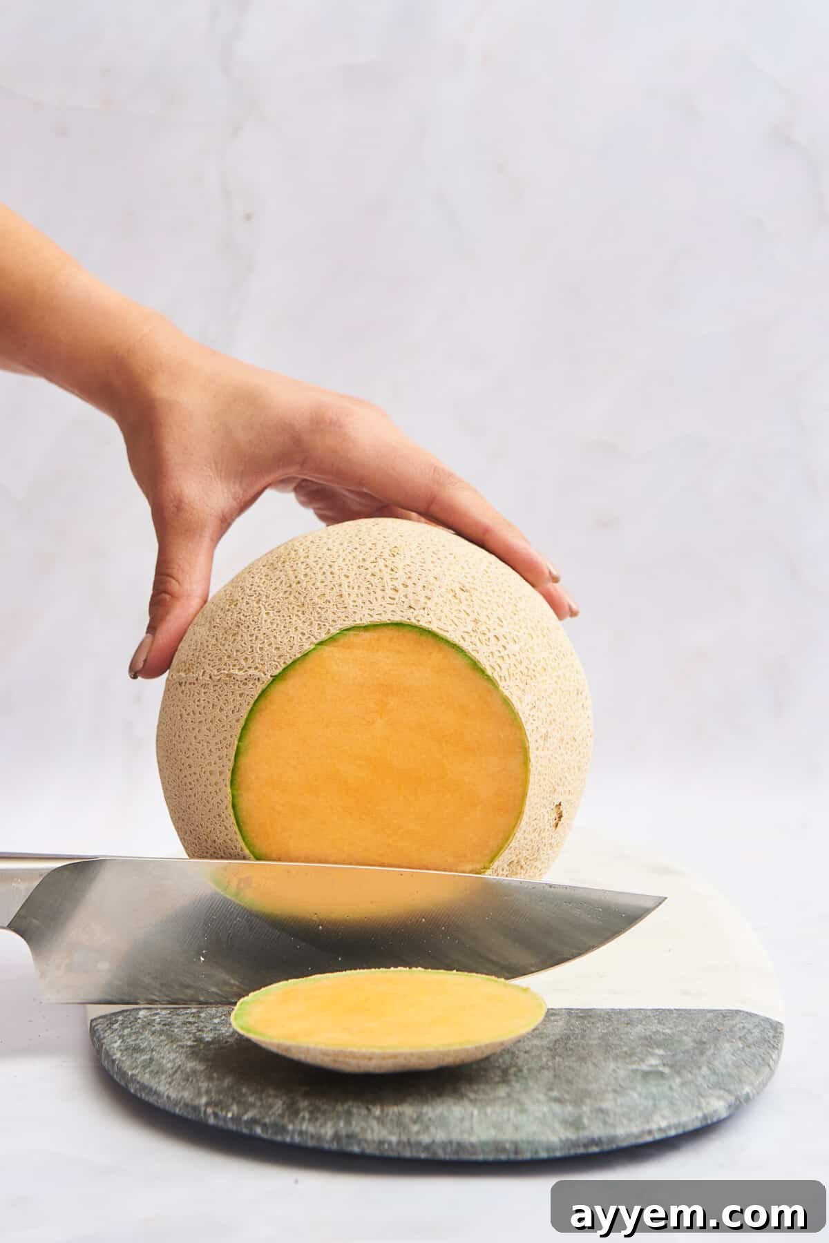 The end of a cantaloupe being sliced off for stability.