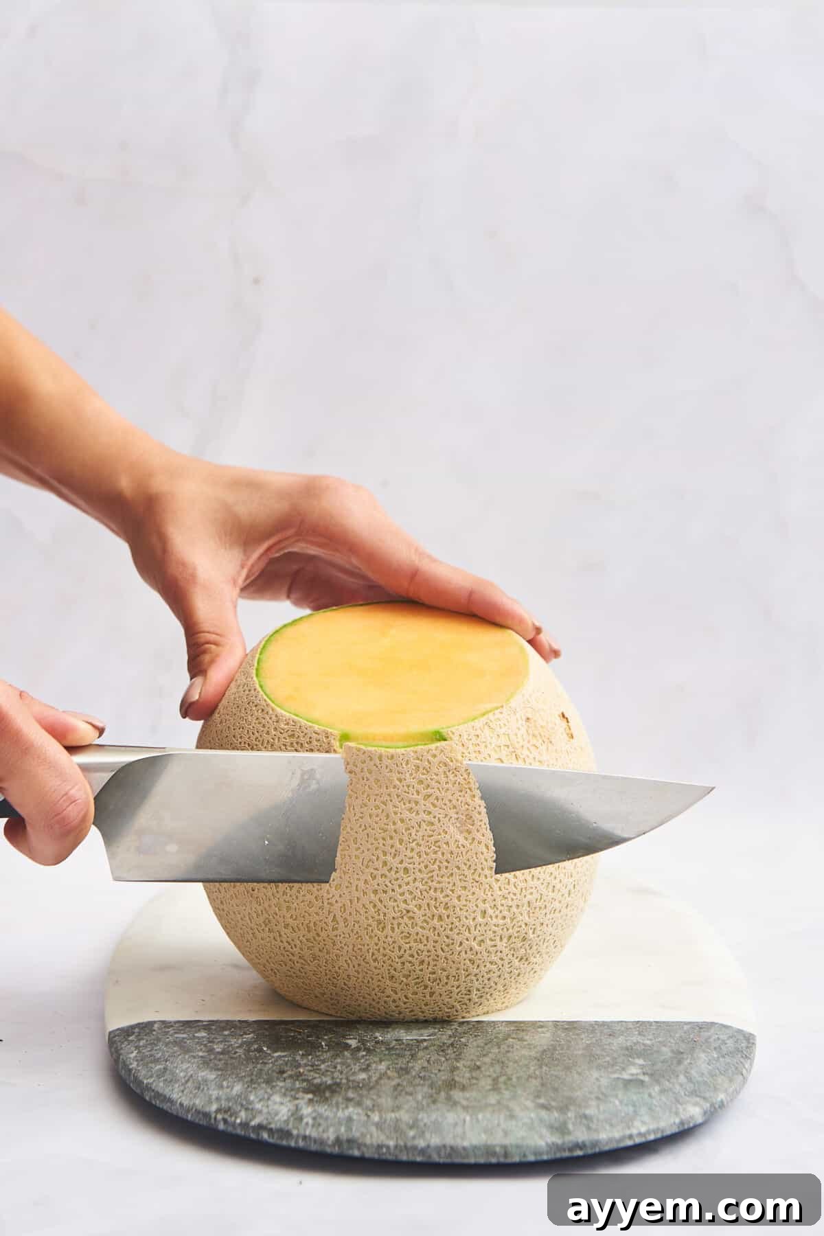 The skin being removed from a cantaloupe with careful knife strokes.