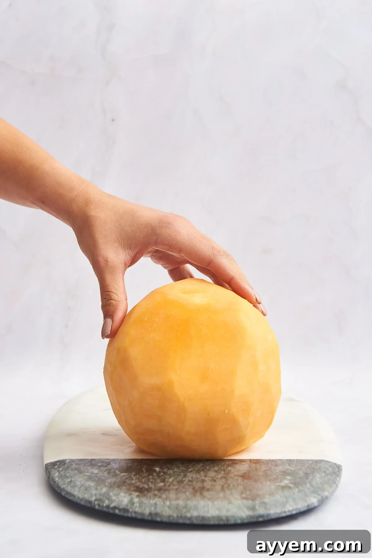 A perfectly peeled cantaloupe, ready for the next cutting step.