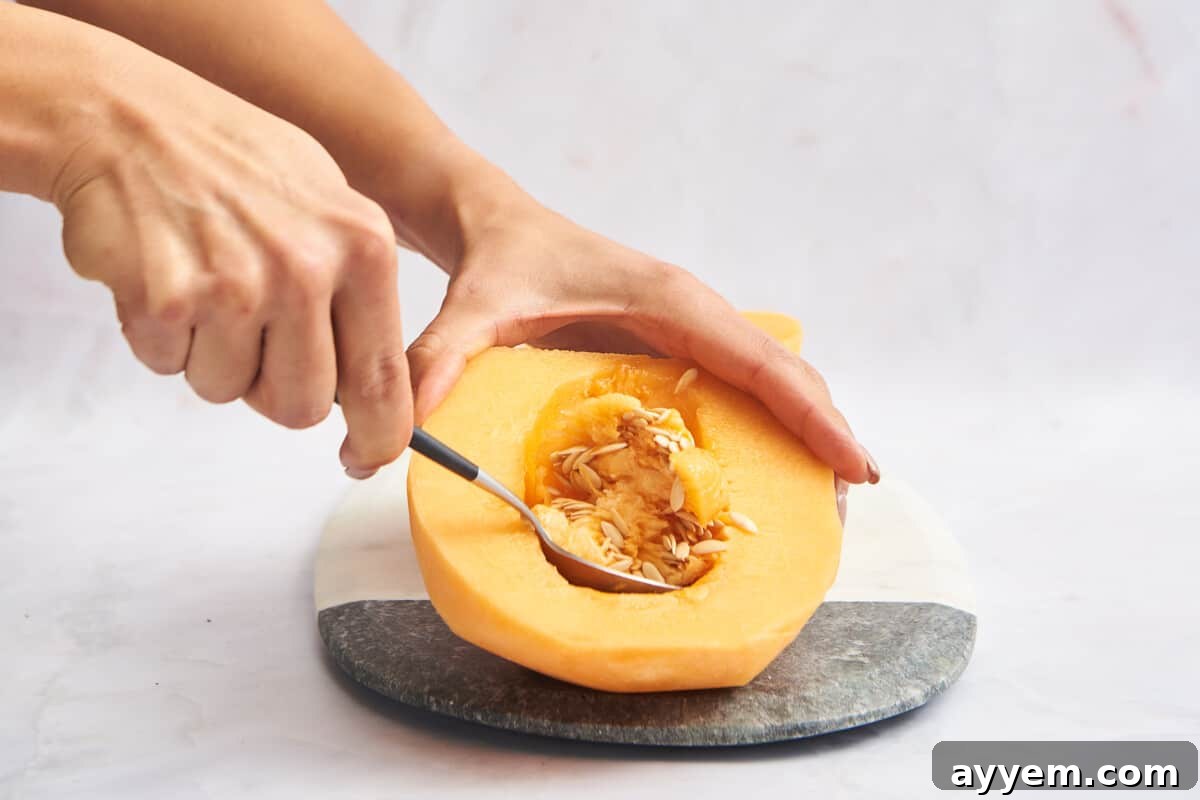 A spoon scooping the seeds and fibrous membrane from a cantaloupe half.