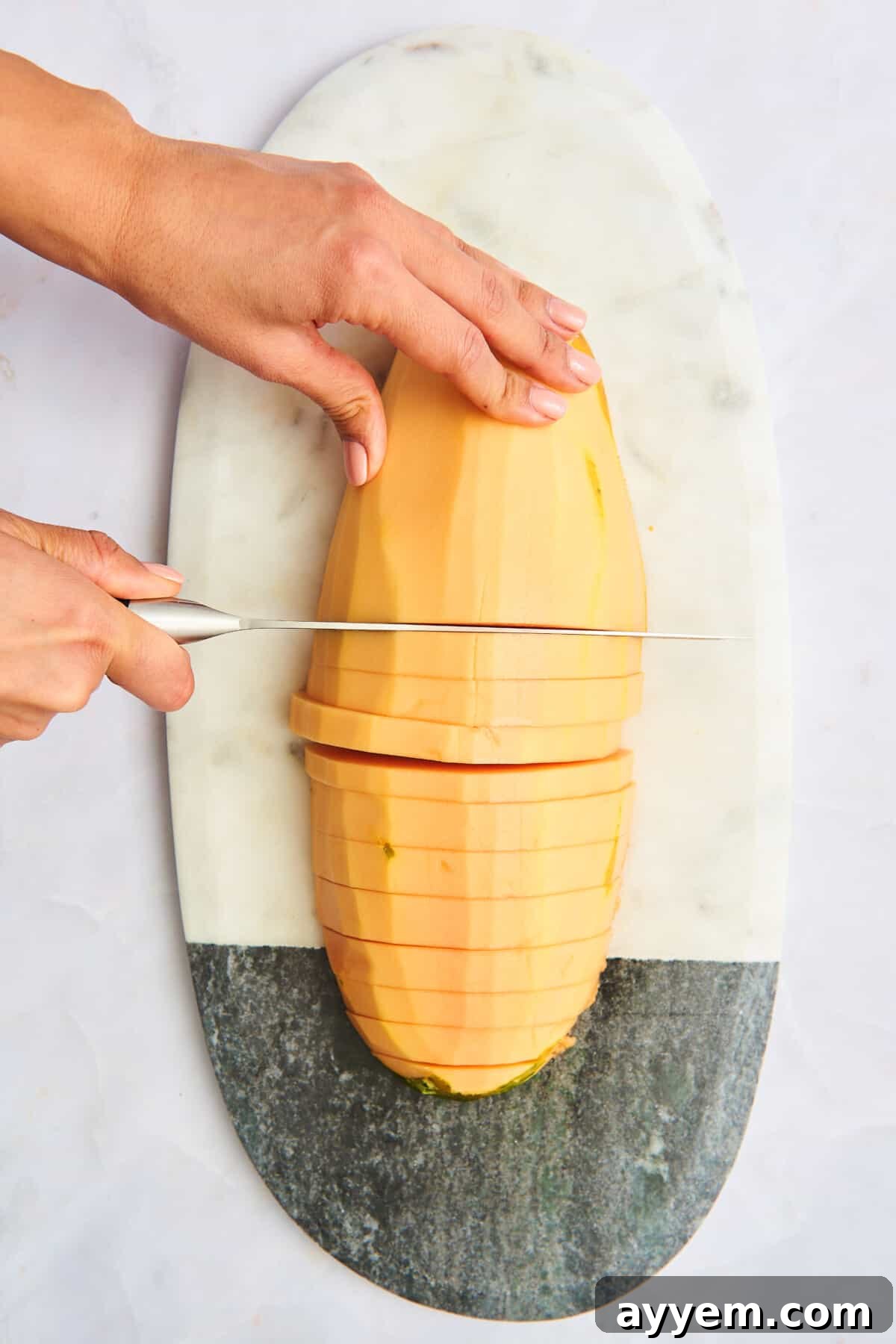 A papaya being cut into long strips.