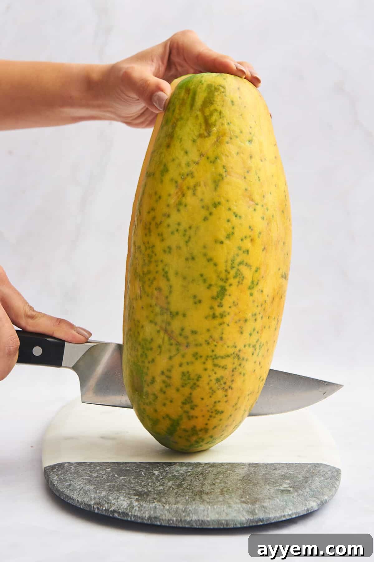 A knife slicing a papaya in half.