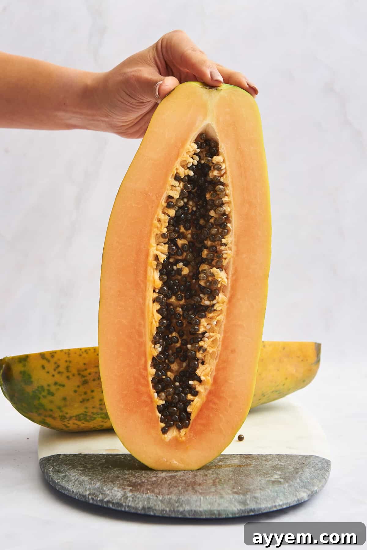A hand holding a halved papaya.