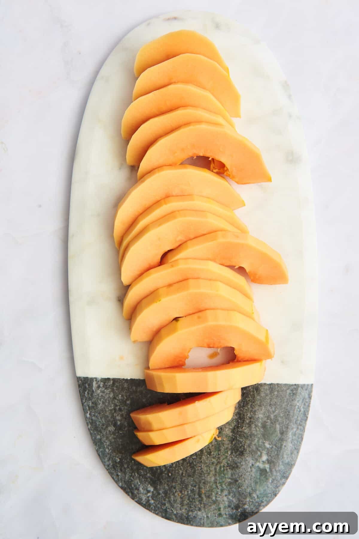 Half moon pieces of papaya on a cutting board.