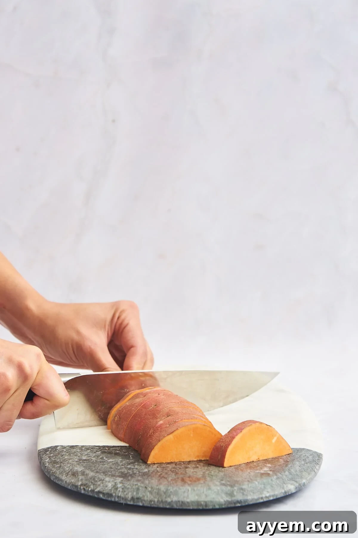 A sweet potato being expertly sliced into wedges.