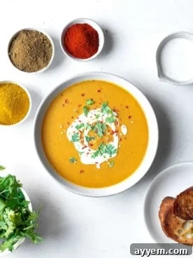 A vibrant bowl of Egyptian lentil soup, garnished with fresh herbs and surrounded by aromatic spices.