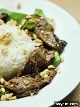 A neatly plated dish of tender beef stir-fry with bright green snow peas, served alongside a mound of fluffy white rice.