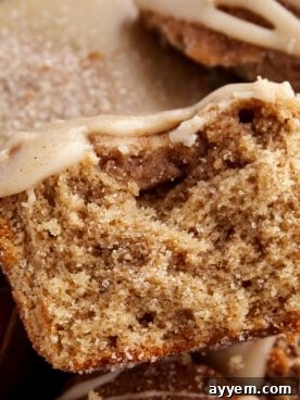 A close-up shot of half a maple-glazed apple cider muffin, showing its tender crumb and glistening topping.