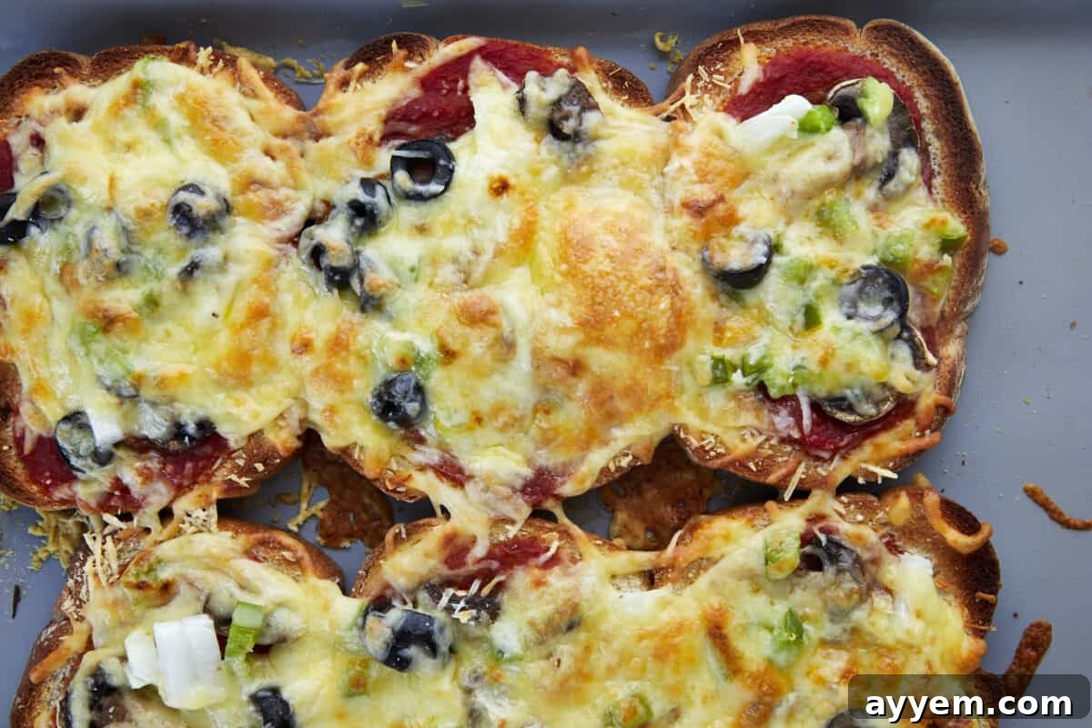 Baked sheet pan pizza made with bread pieces on a baking sheet, ready to be sliced and served.