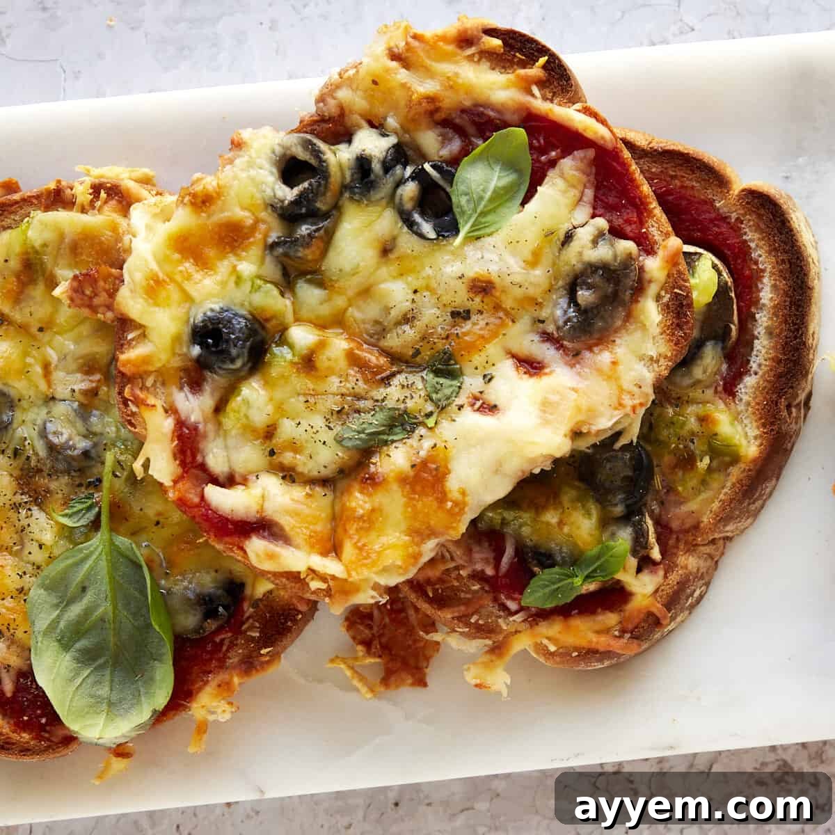 Slices of sheet pan pizza on a plate, garnished with fresh basil.