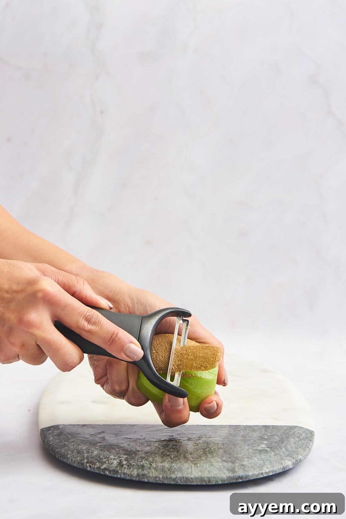 Slice Your Kiwi Like a Pro 5 A vegetable peeler being used to efficiently remove the skin from a kiwi, offering an alternative peeling technique.