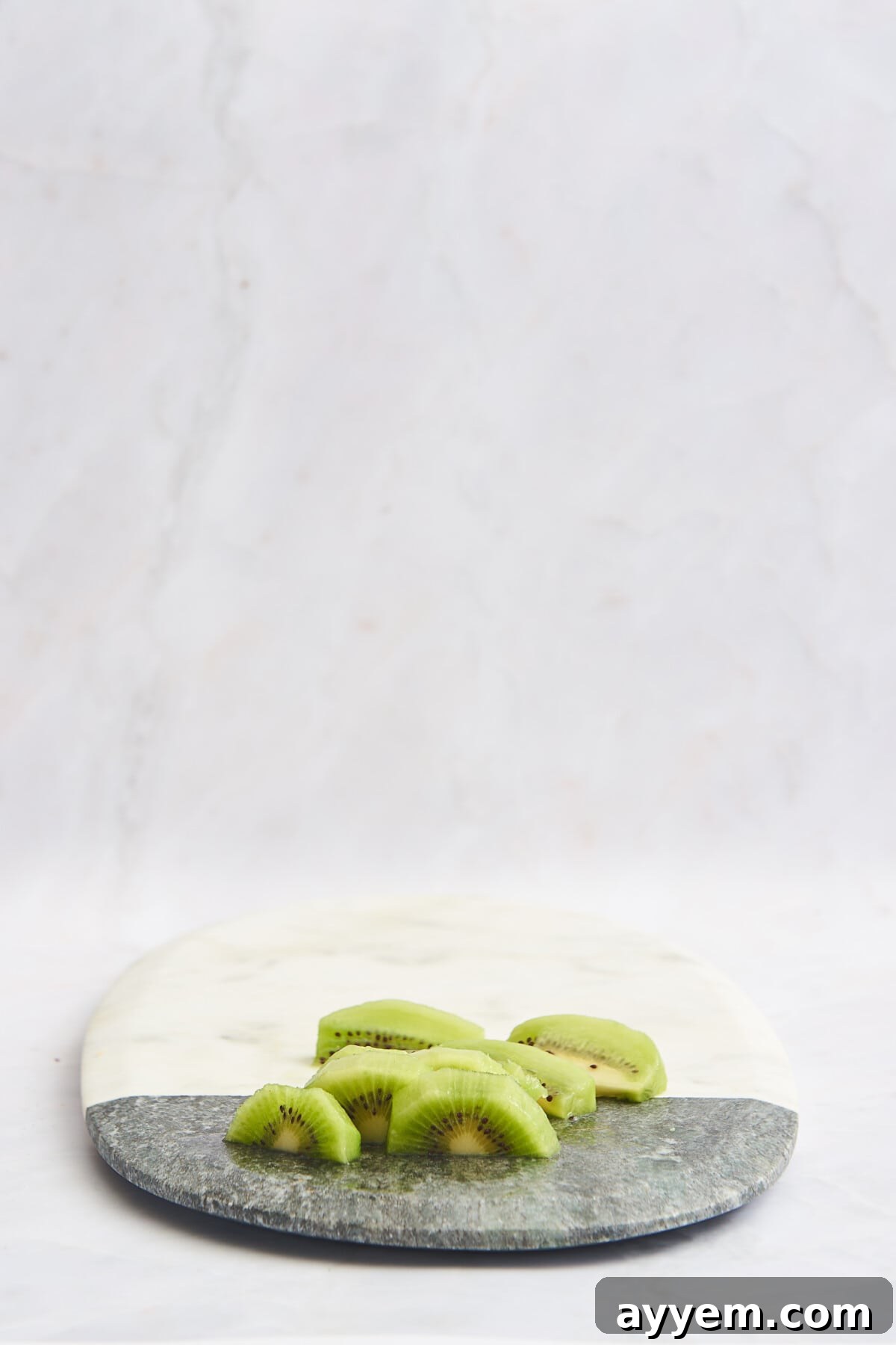 Slice Your Kiwi Like a Pro 9 Skinless kiwi chunks on a marble cutting board, ready for consumption or use in recipes.