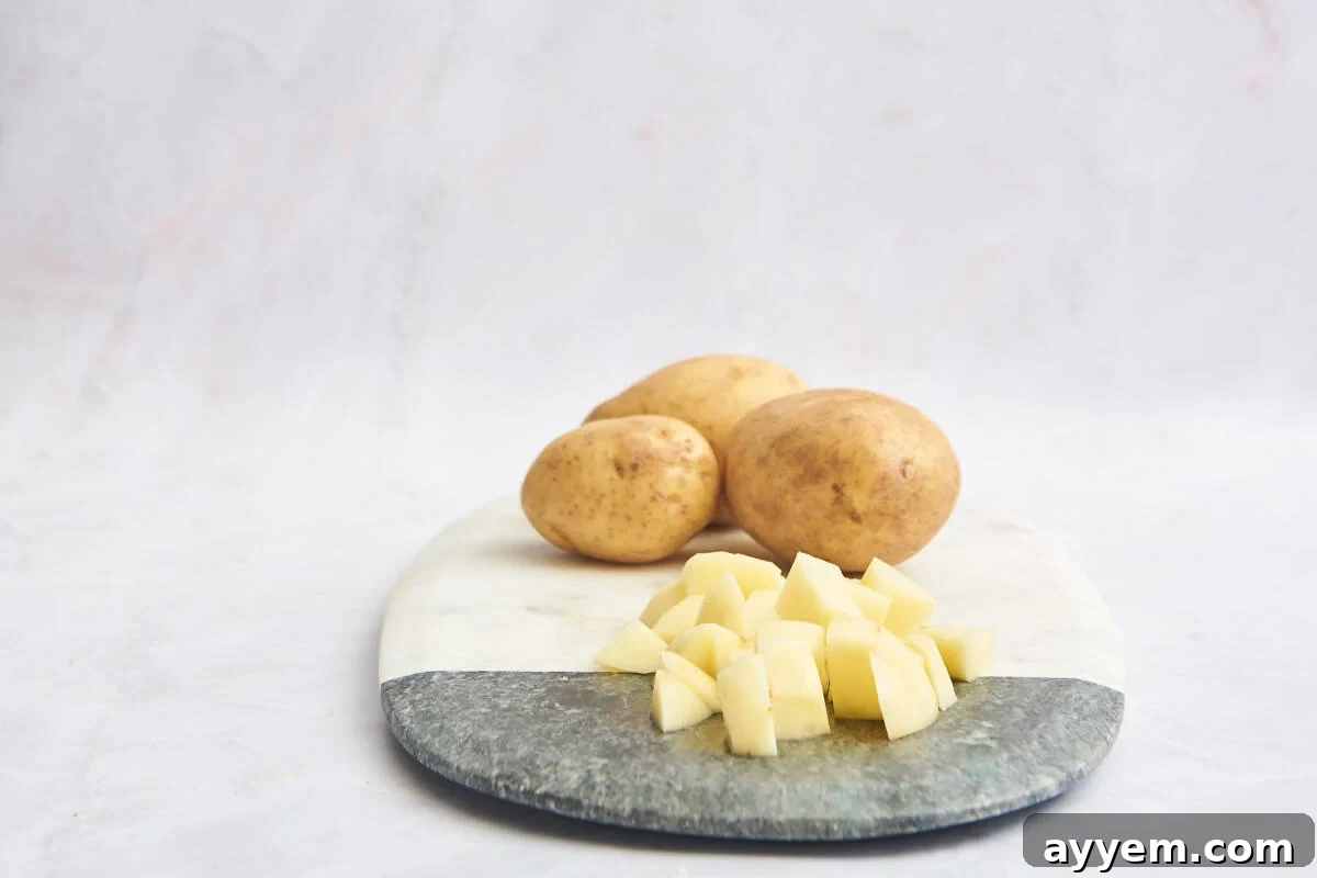 A vibrant display of whole and perfectly cubed potatoes arranged on a wooden cutting board, highlighting the final cut.