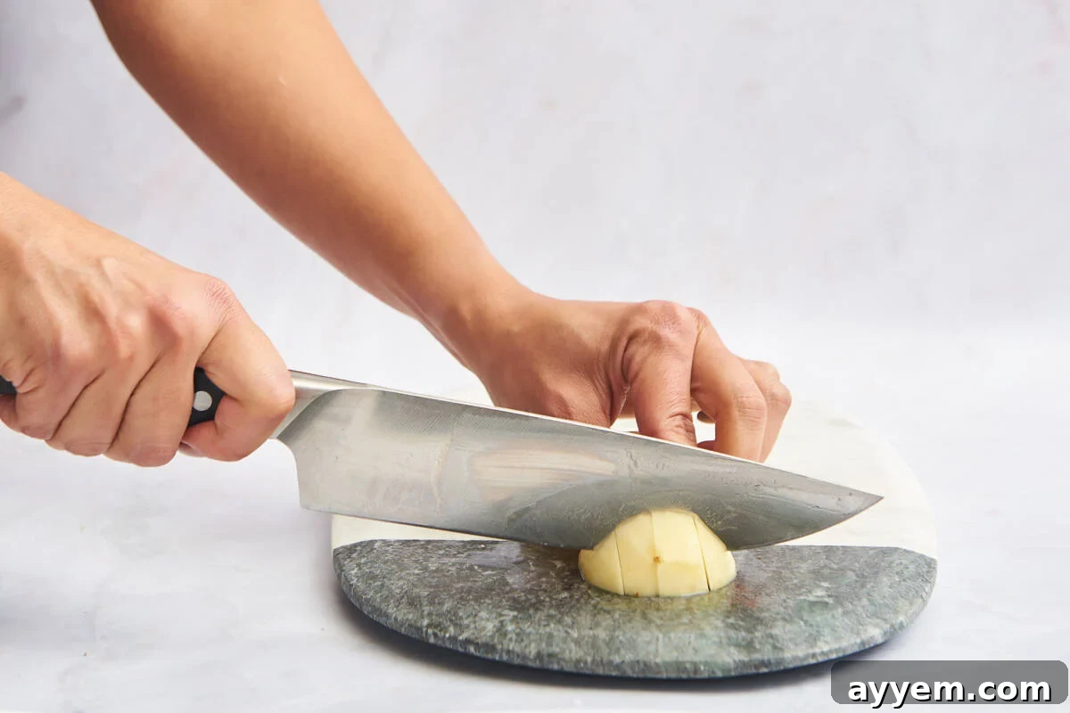 Potato sticks being cut widthwise into cubes.