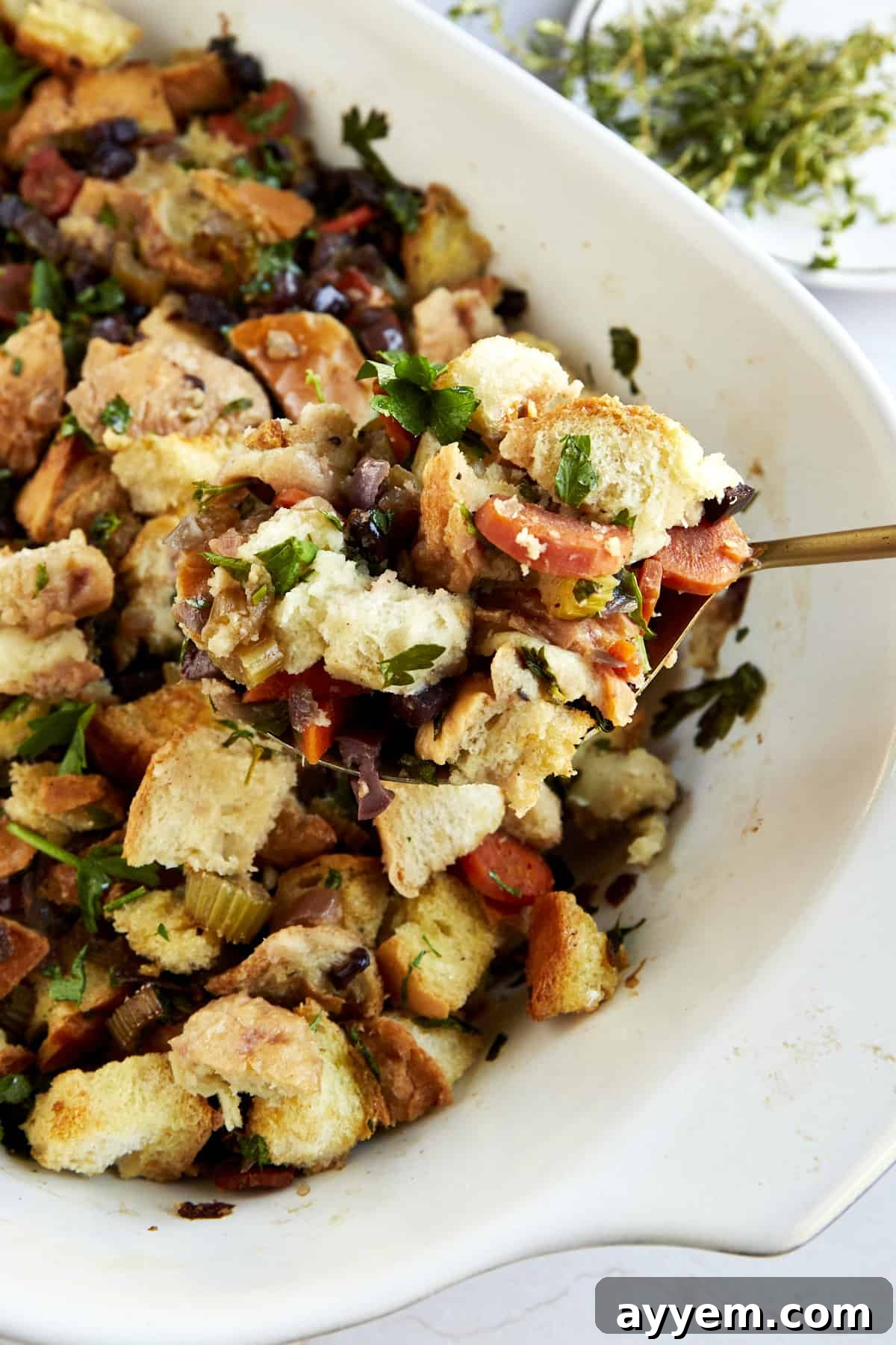 Flavorful Mediterranean Stuffing 2 A spoon scooping up a bite of bread stuffing from a baking dish.