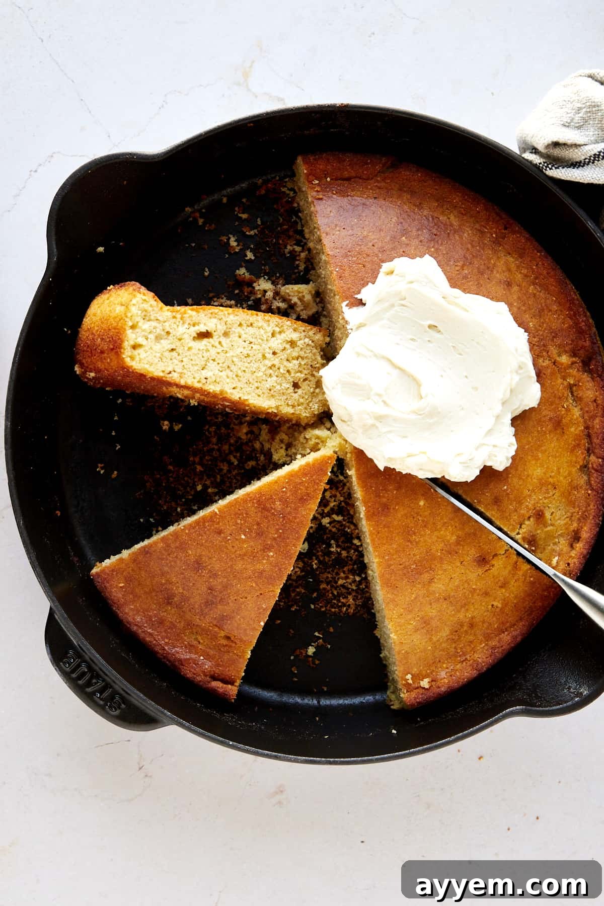 Half a skillet of brown butter cornbread topped with whipped butter and two pieces on the other side. 