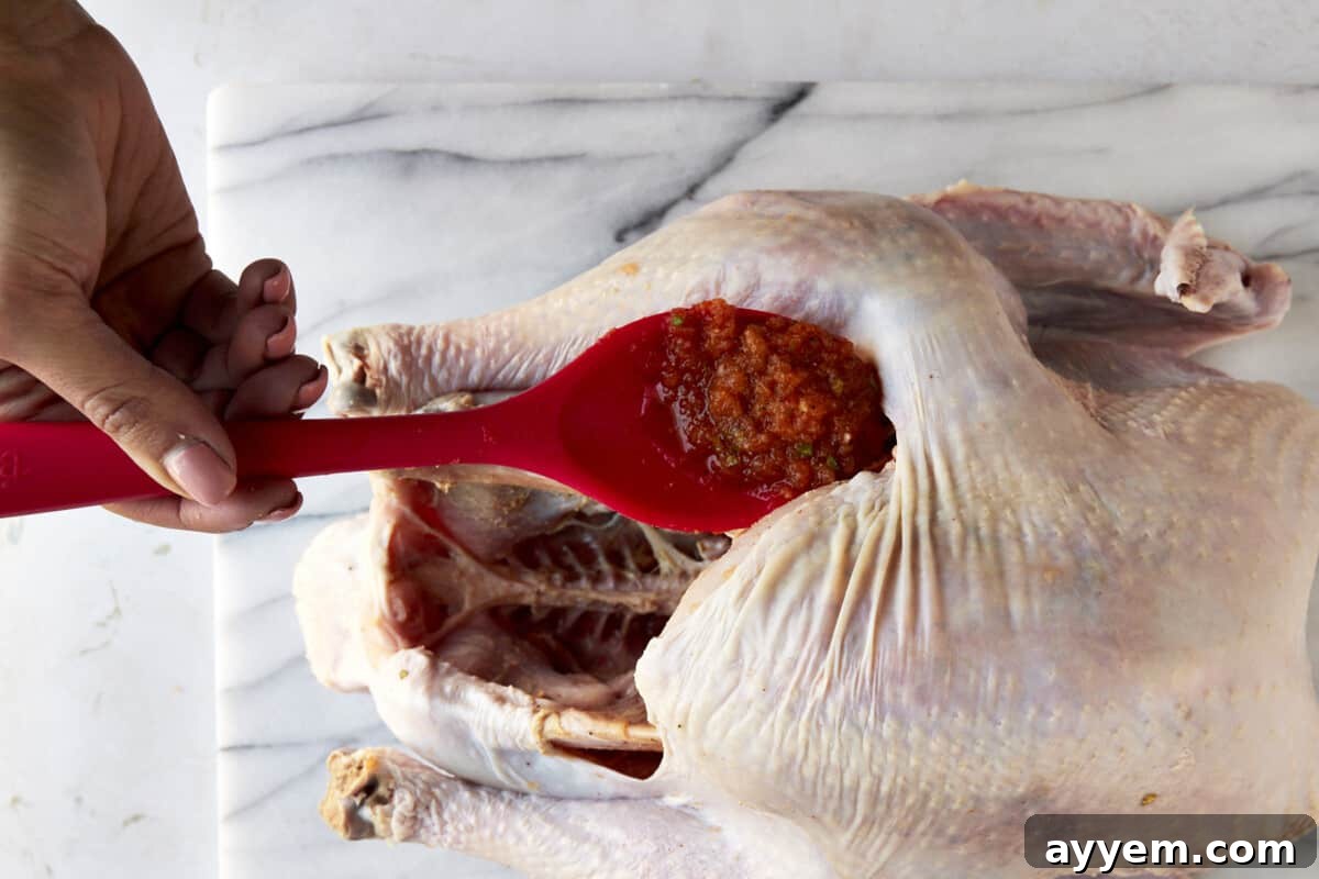 Spreading turkey rub underneath the skin for deep flavor infusion.