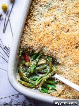 A baking dish filled with a creamy, cheesy green bean casserole, with a portion scooped out.