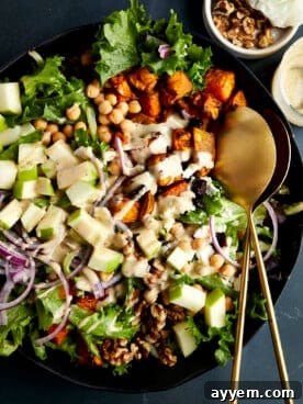 A vibrant bowl of sweet potato salad with chickpeas, generously drizzled with a creamy tahini dressing.