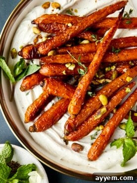 Oven-roasted carrots adorned with fresh mint and pistachios, drizzled with a rich tahini dressing.