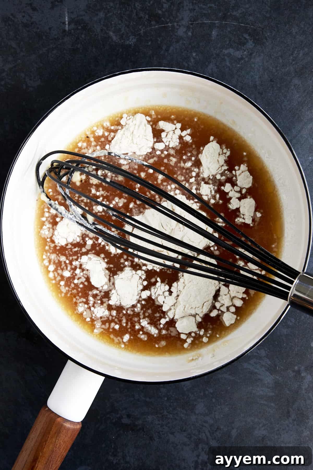 A roux being made with turkey drippings and flour in a saucepan, showing the golden-brown mixture.