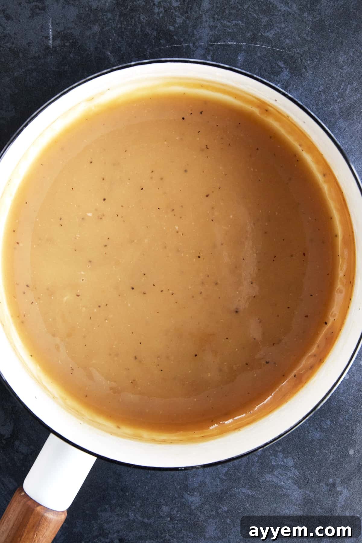 Homemade turkey gravy simmering in a saucepan, showing its smooth, rich consistency.