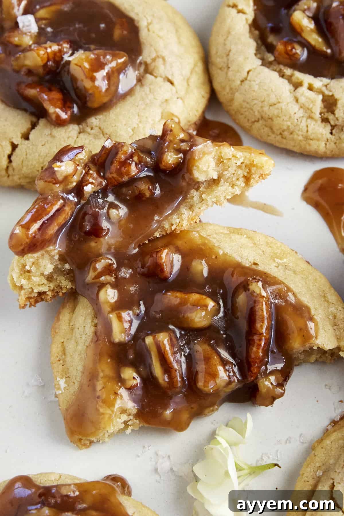 A pecan pie cookie, cut in half, revealing the rich, gooey pecan filling and the soft, buttery cookie base.