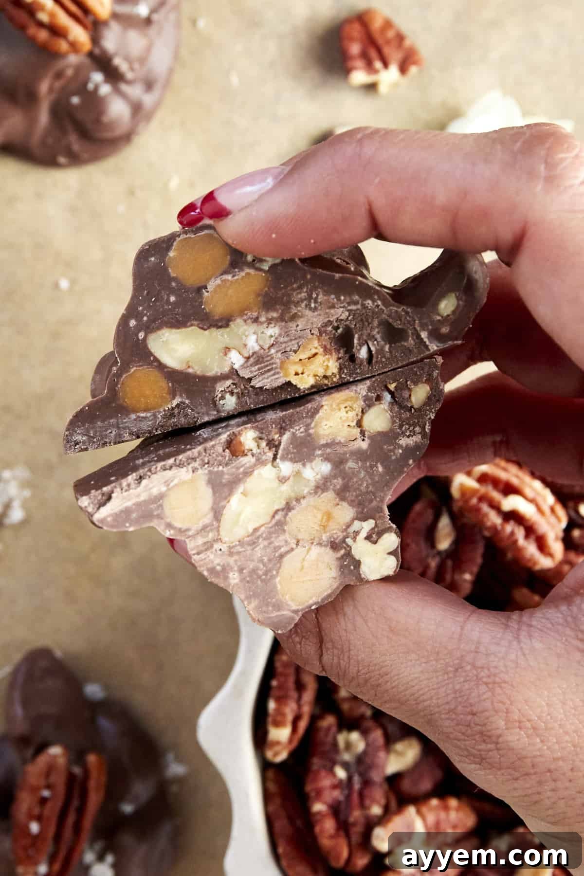 A tantalizing view of two halves of a chocolate caramel pecan cluster, revealing its rich layers and inviting texture.