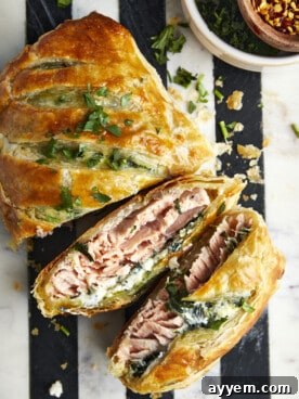 Two slices of golden-brown Salmon Wellington revealing flaky pastry, tender salmon, and a creamy filling.