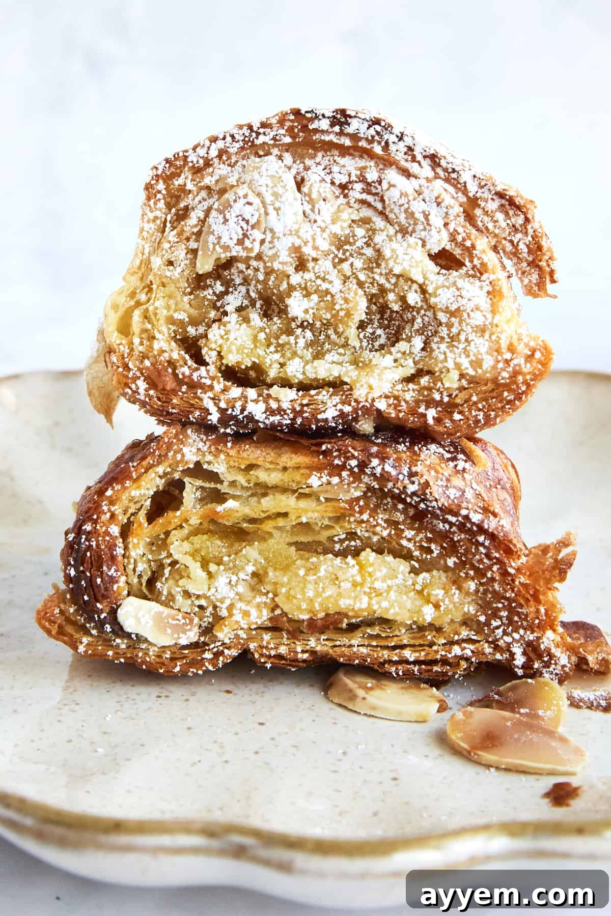 Two pieces of almond croissant French toast stacked and dusted with powdered sugar, ready to be eaten.