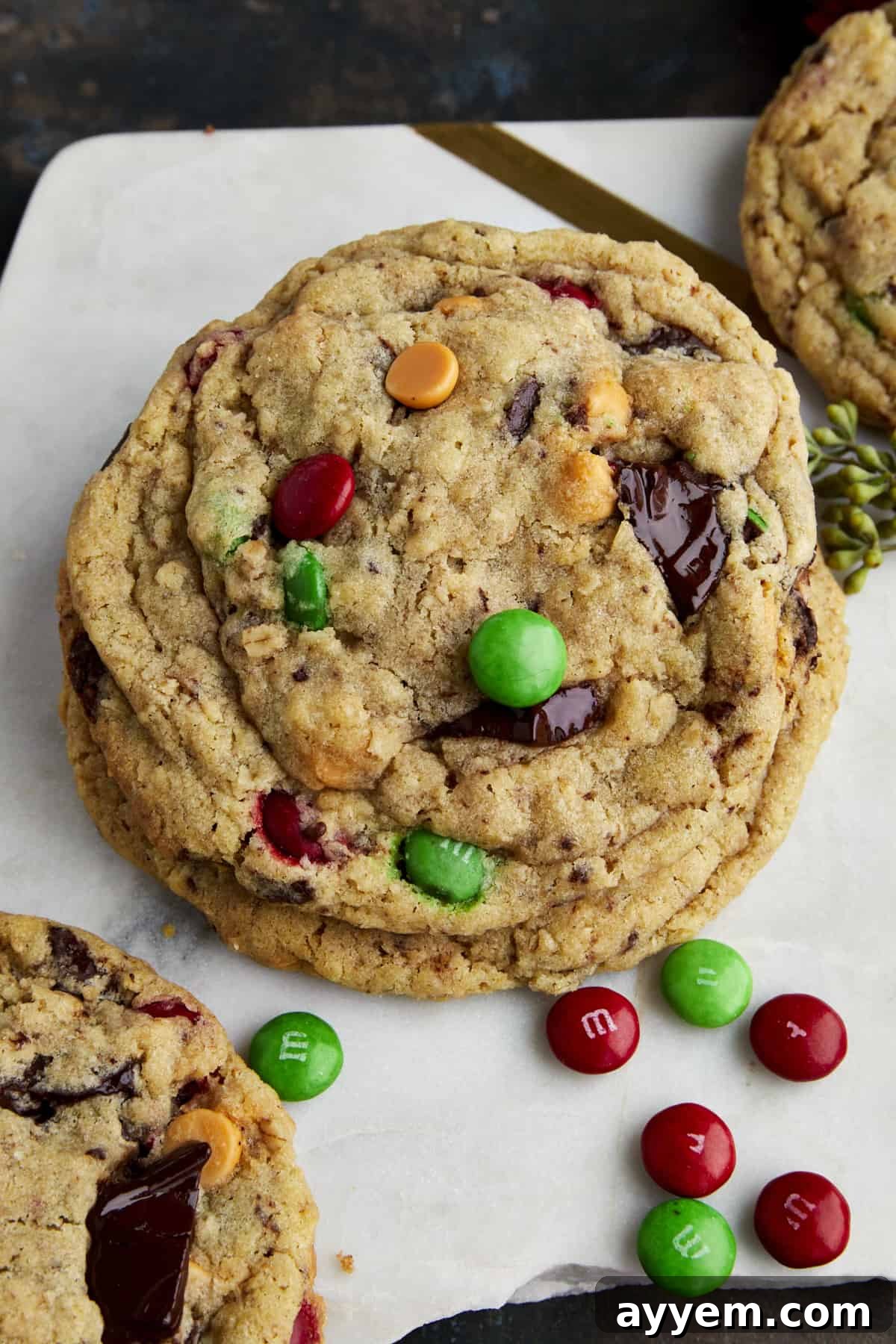 Two Christmas monster cookies stacked on top of each other, showcasing their generous mix-ins and inviting texture. Ideal for holiday gifting or sharing.