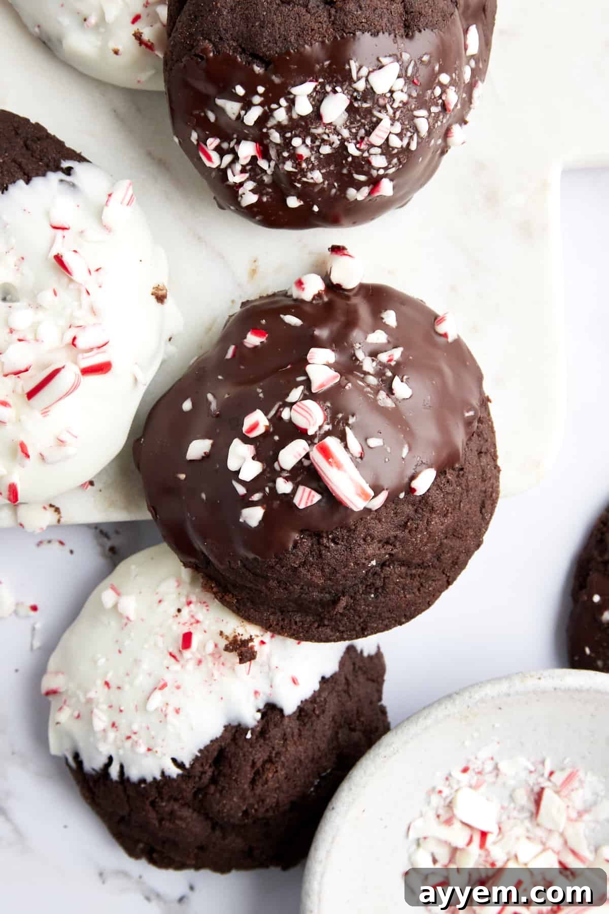 Soft and chewy chocolate peppermint cookies, half-dipped in white chocolate and sprinkled with crushed candy canes, arranged beautifully on a platter.