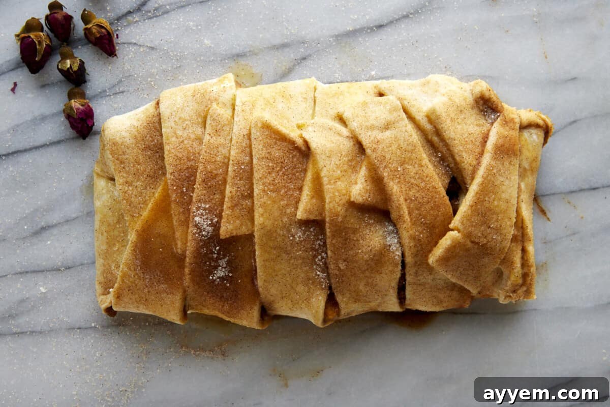 An unbaked apple puff pastry braid, showing the layered filling and braided dough strips before going into the oven.