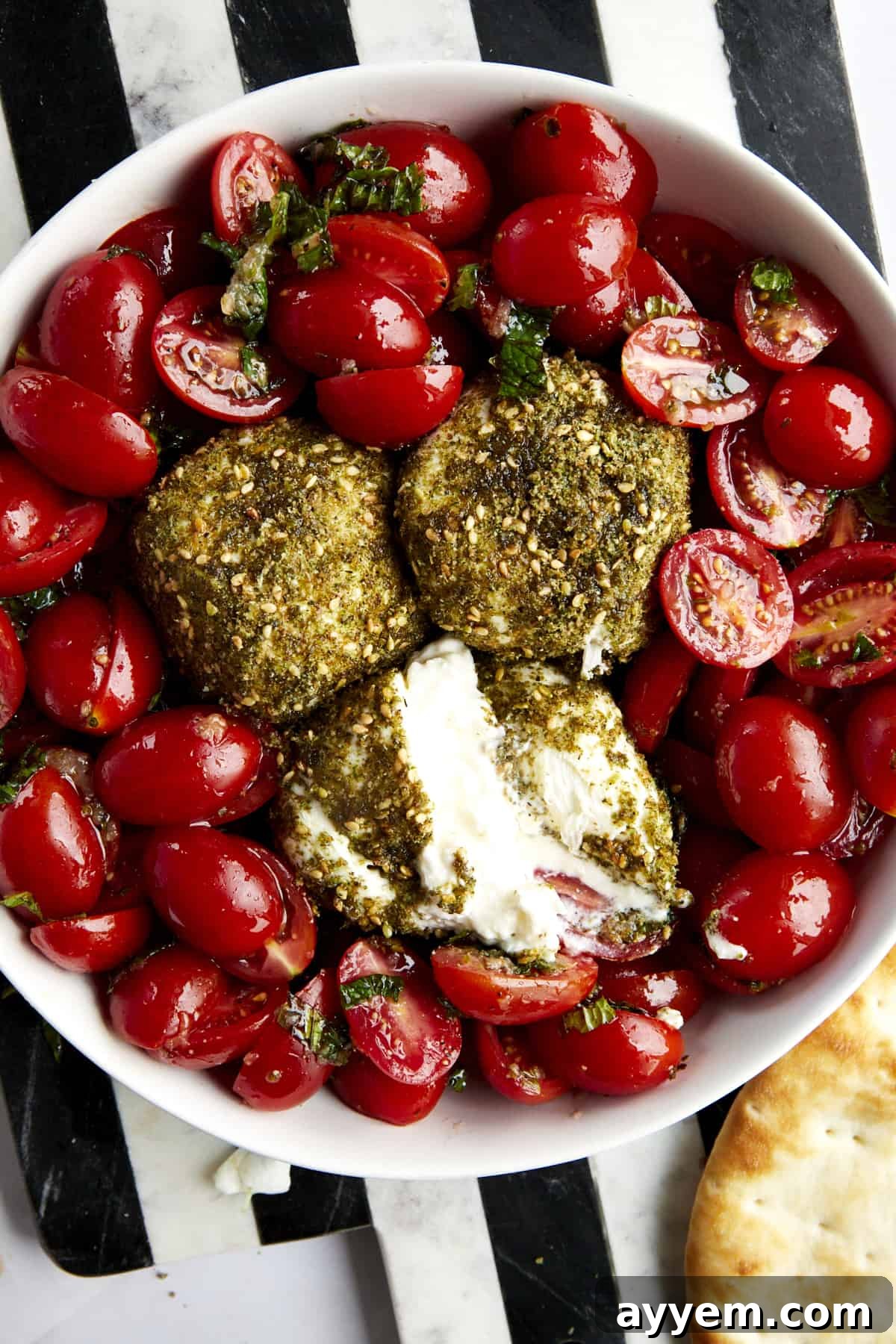 A close-up view of the Tomato and Burrata Salad with Za'atar, showcasing the beautifully coated burrata and colorful tomatoes, garnished with fresh mint. The image captures the fresh and inviting nature of this flavorful dish.
