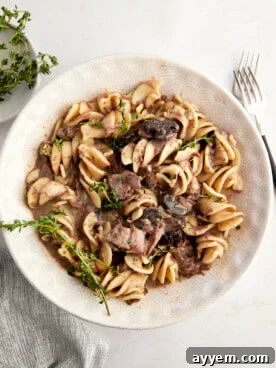 A bowl of slow cooker beef stroganoff, rich and creamy, garnished with fresh parsley.