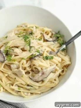 A creamy bowl of one-pot chicken tetrazzini with a fork, garnished with fresh herbs.