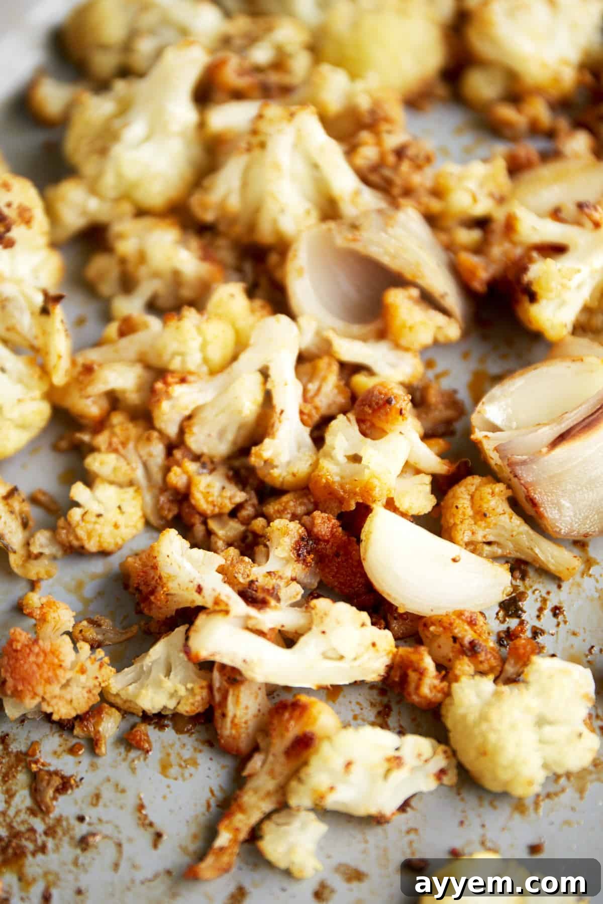 Roasted cauliflower, shallots, and onions on a baking sheet. 