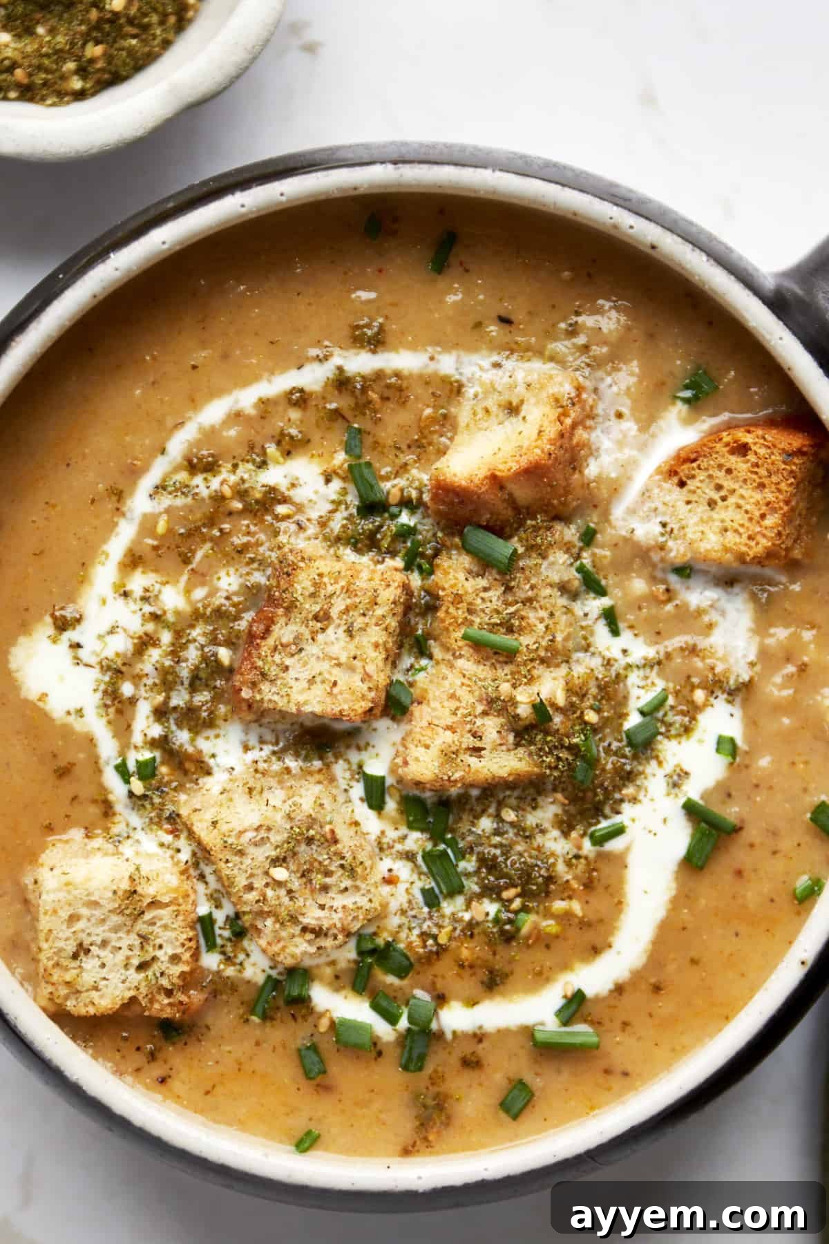 A bowl of roasted cauliflower soup topped with heavy cream, croutons, and za'atar. 