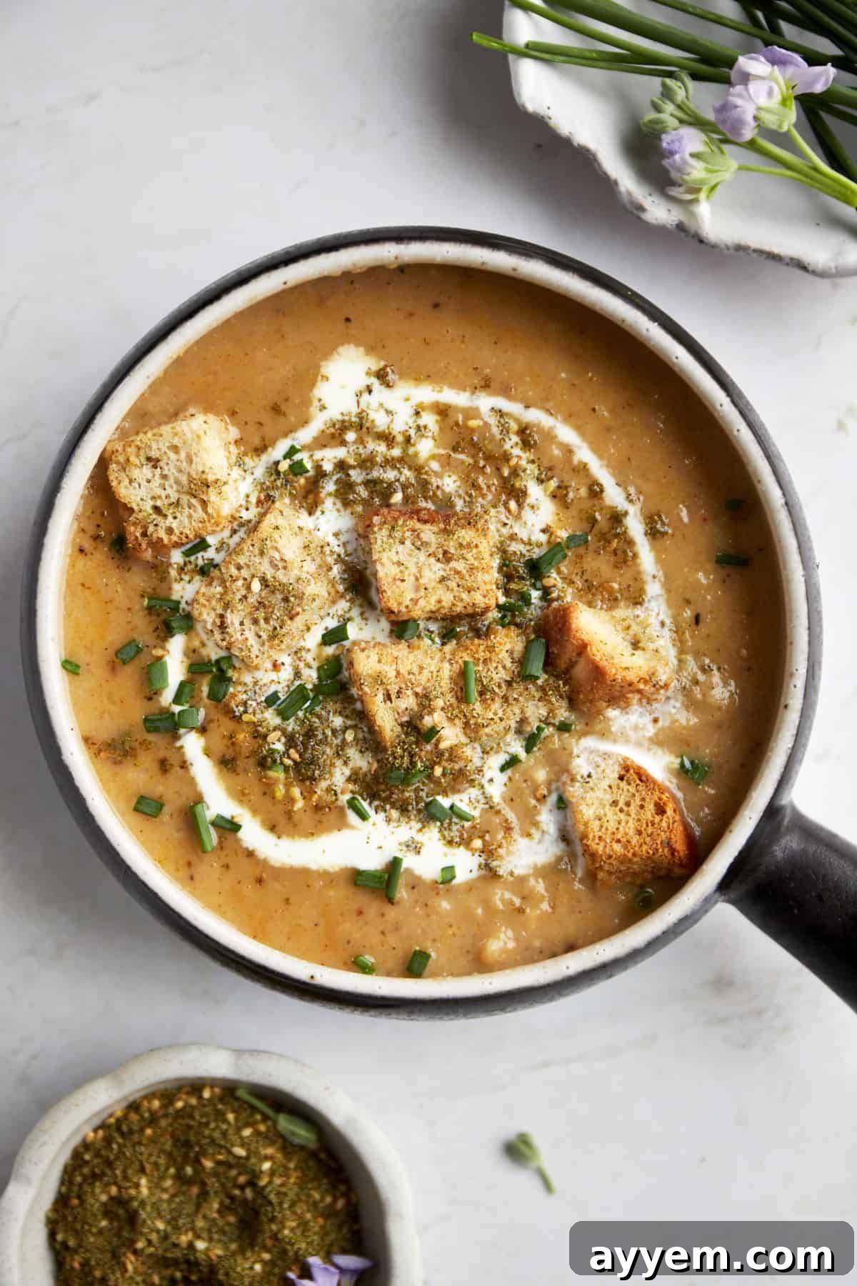 A bowl of roasted cauliflower soup topped with heavy cream, croutons, and za'atar.