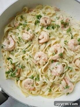 A beautifully plated bowl of creamy linguine shrimp alfredo, featuring succulent, perfectly cooked shrimp coated in a rich, velvety Parmesan sauce with fresh herbs.