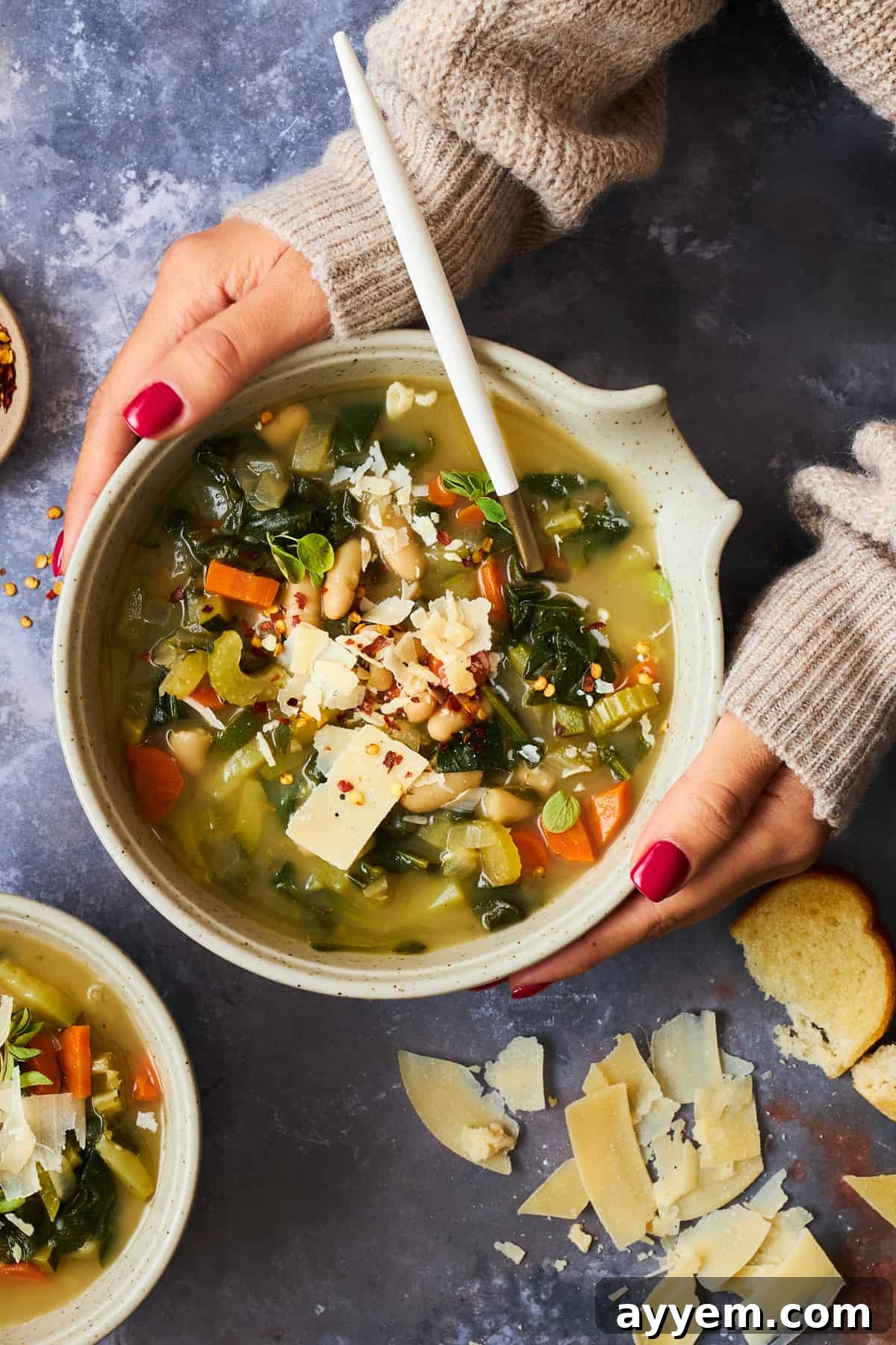 Two hands holding a bowl of cannellini bean soup. 