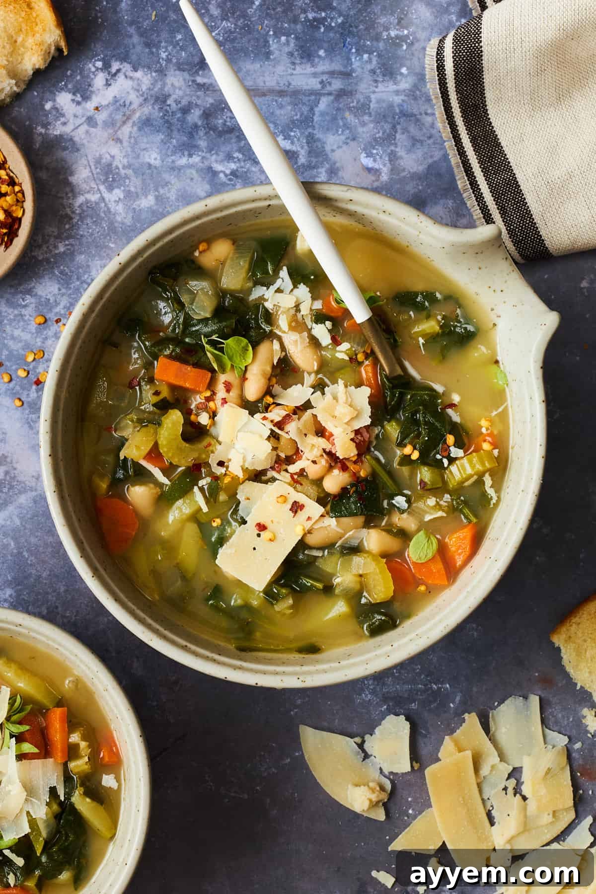 A bowl of cannellini bean soup with vegetables topped with parmesan. 