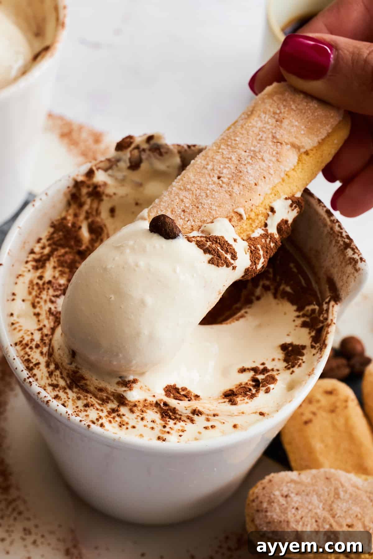 A ladyfinger cookie being dipped into a bowl of creamy Tiramisu Dip, highlighting its rich texture and appealing presentation.